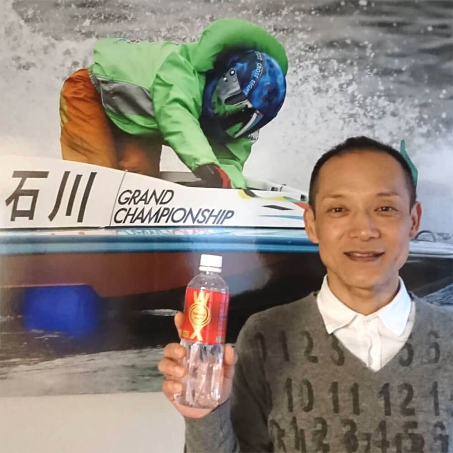 Powerboat racer holding WOX in front of a championship poster