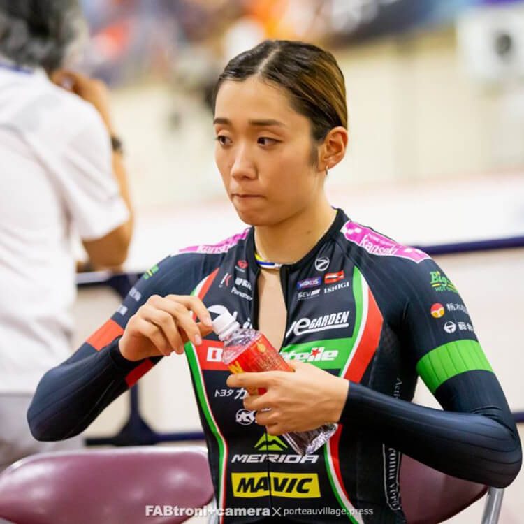 Track cyclist in team kit opening a bottle of WOX at the velodrome