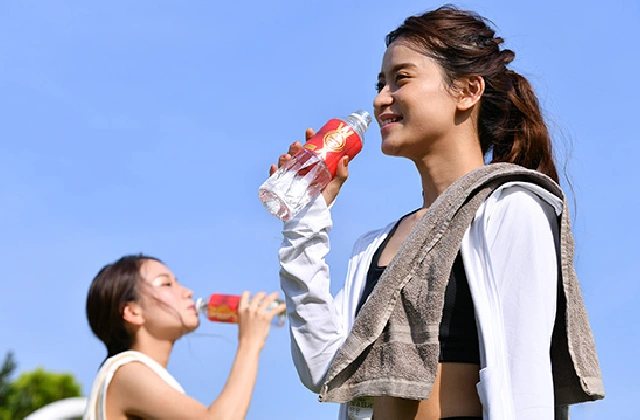 Two people drinking WOX outdoors under a clear sky